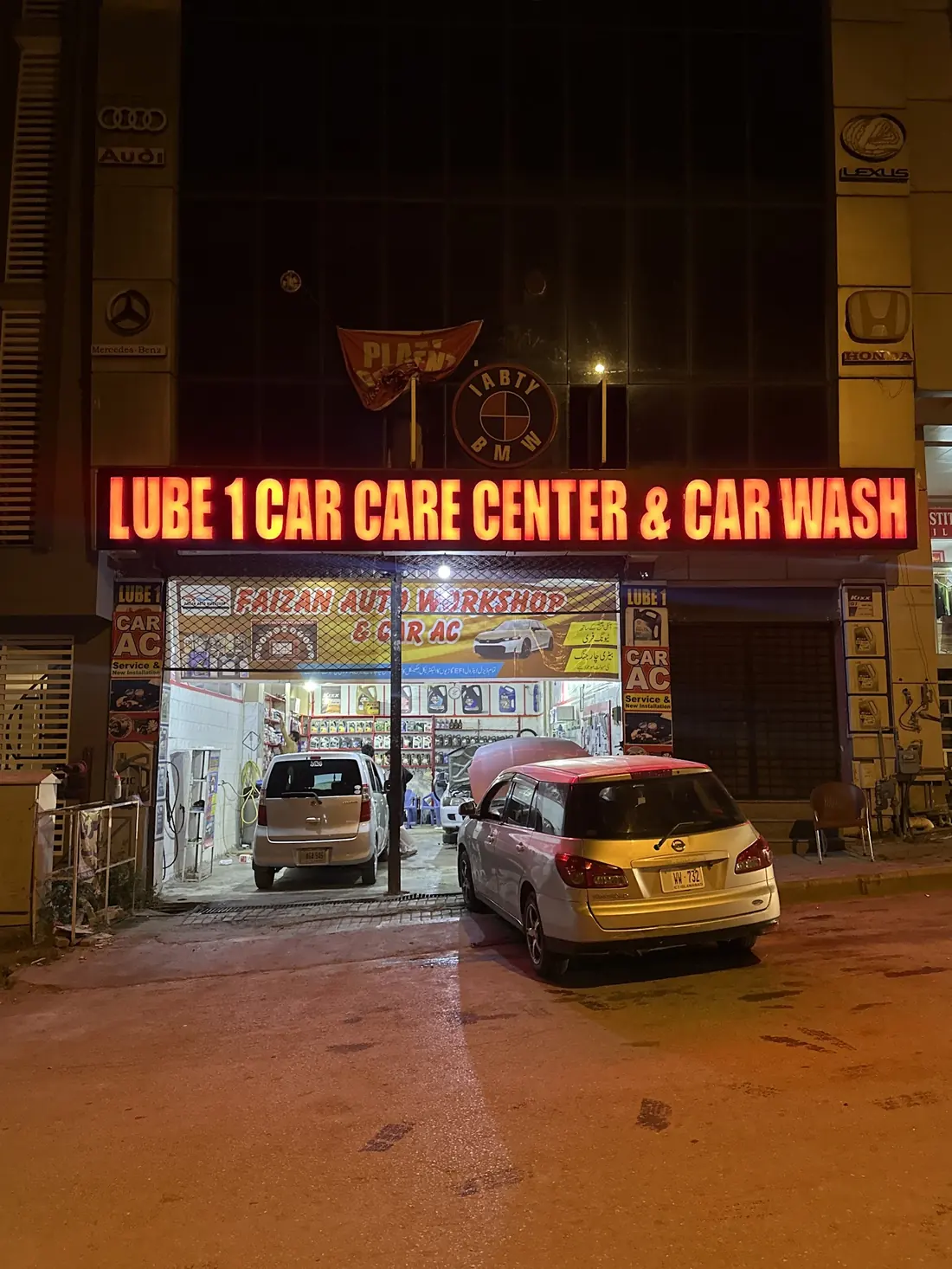 The workshop front at night with the red Lube 1 Car Care Centre sign lit up